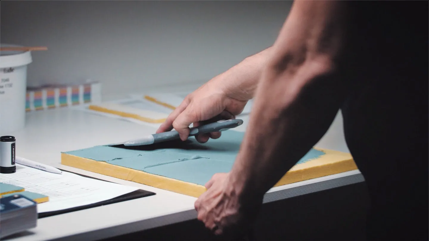 A hand cutting an acoustic panel