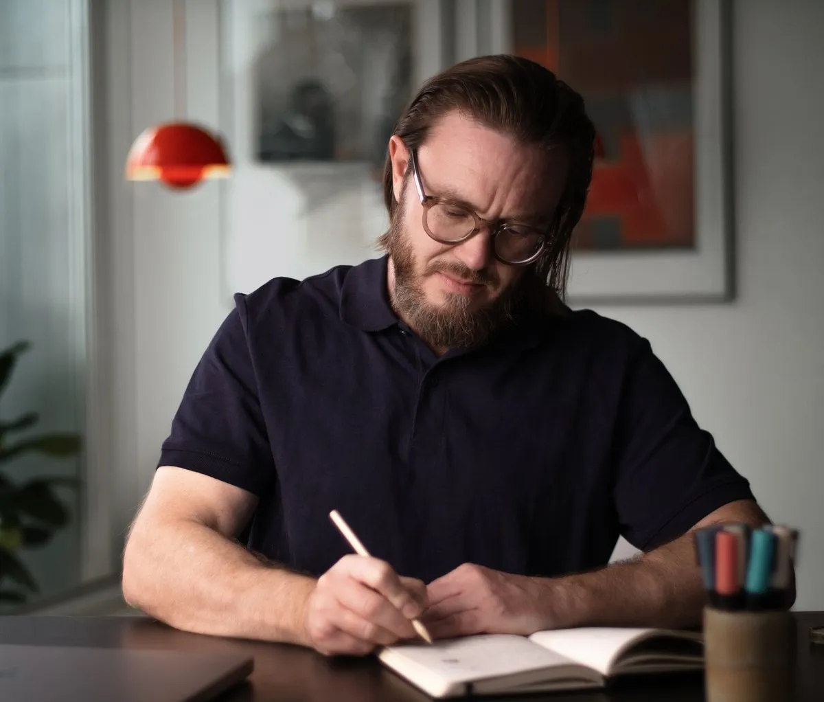Kristoffer Hanghøj skriver noter i en notesbog ved sit skrivebord