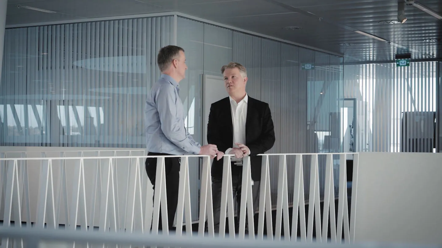To mænd ved et gelænder i Saxo Banks kontormiljø